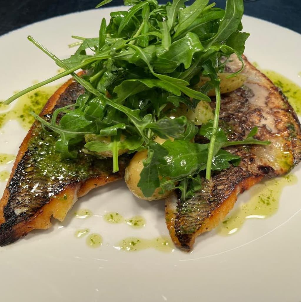 Two pan-fried fish fillets with dressed rocket and herb oil