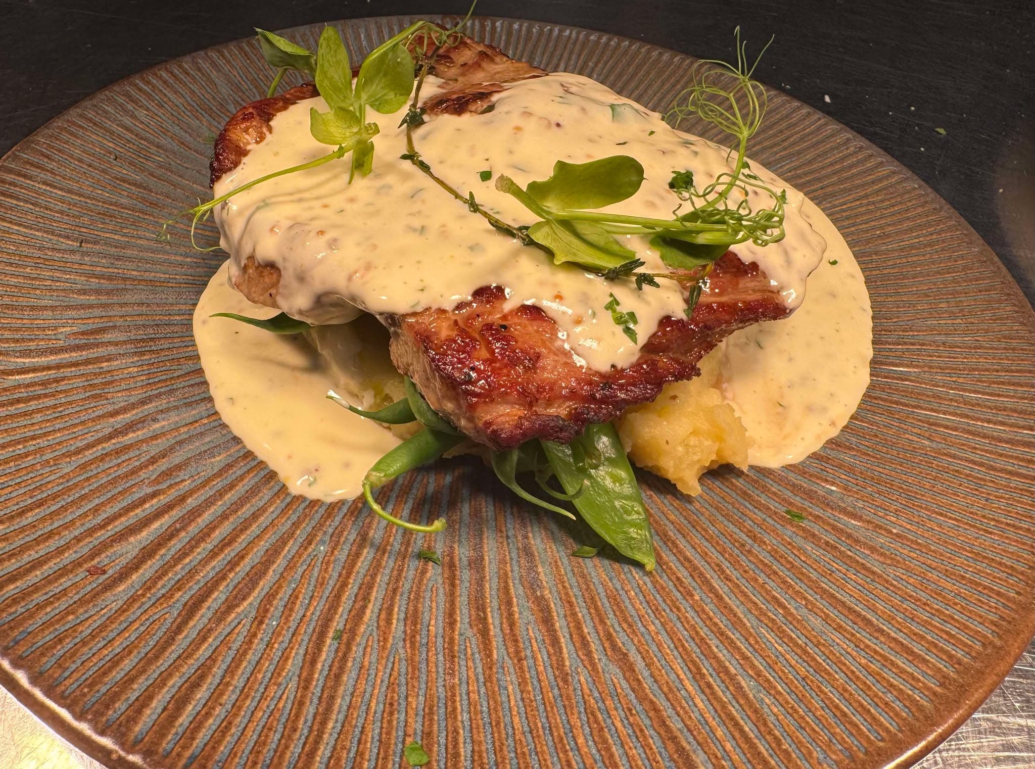 A pan-fried cutlet in a creamy sauce finished with pea shoots